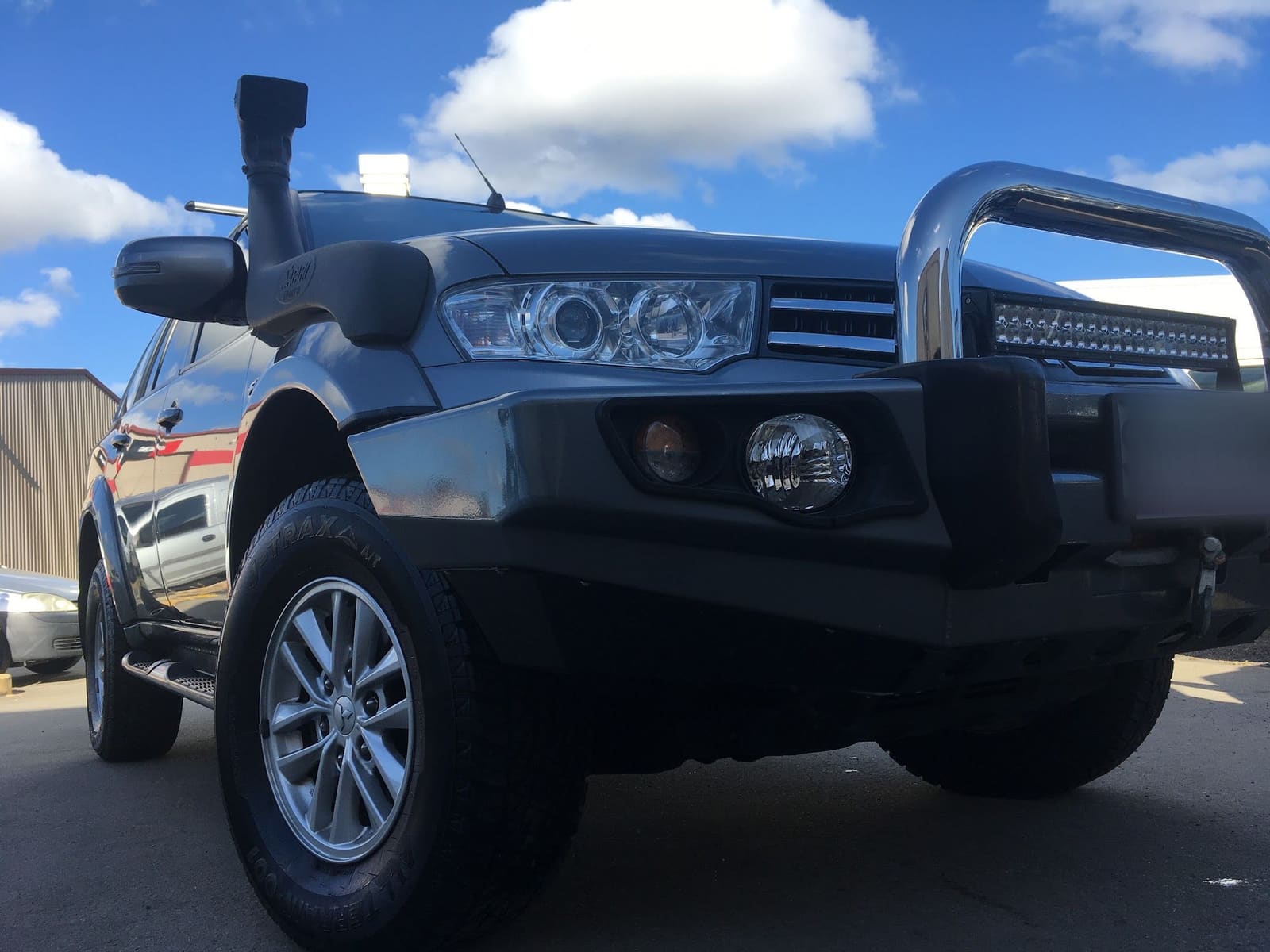A Mitsubishi with a bull bar, snorkel and light bar