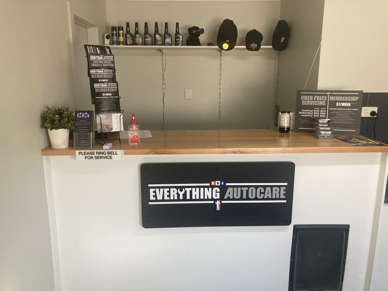 The reception desk with the Everything Autocare sign on the front and a fixed price servicing board on the counter