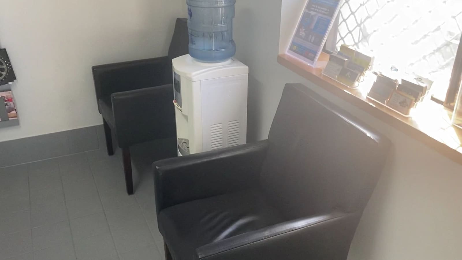 The customer waiting area with two black leather chairs and a water cooler